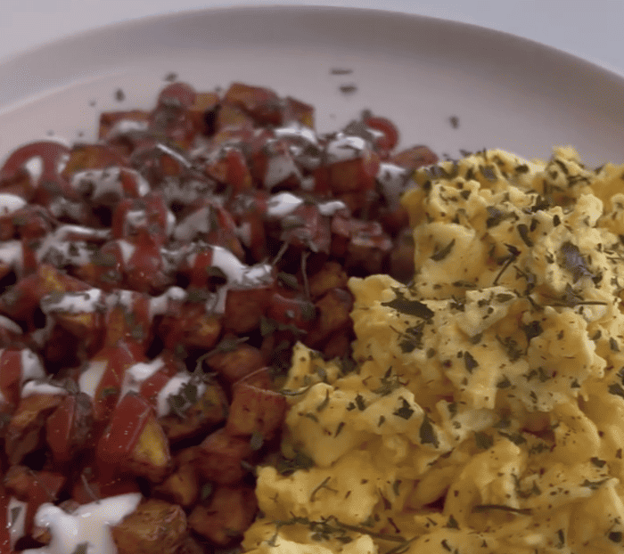 garnished scrambled eggs and potato hash with sauce